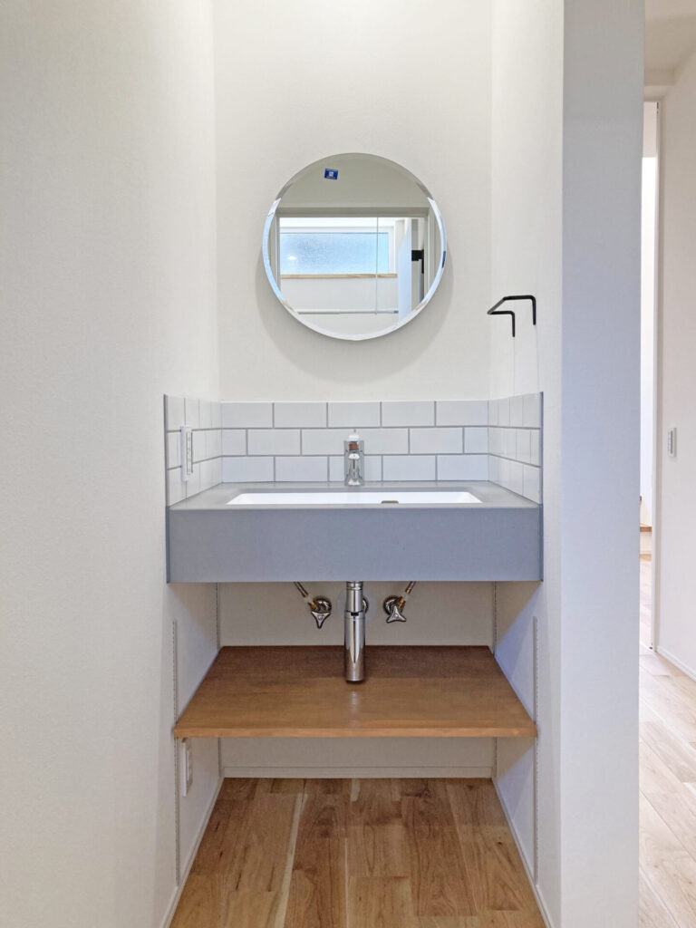 丸い鏡とシックな雰囲気の手洗いスペース